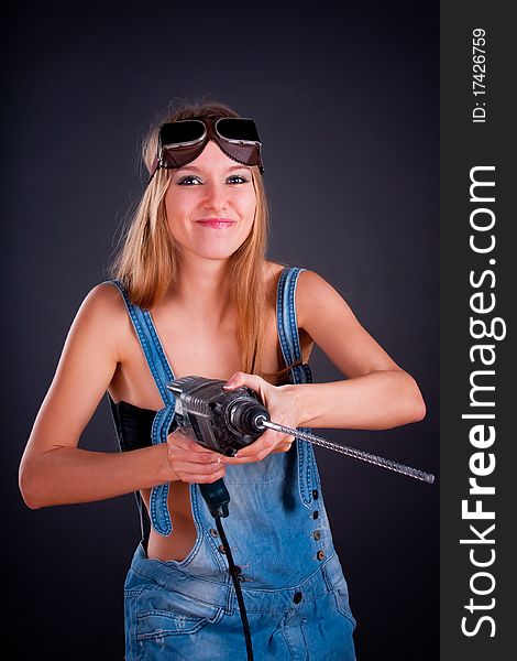 Girl with a drill in building overalls