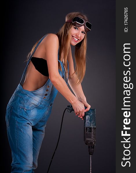 Girl with a drill in building overalls
