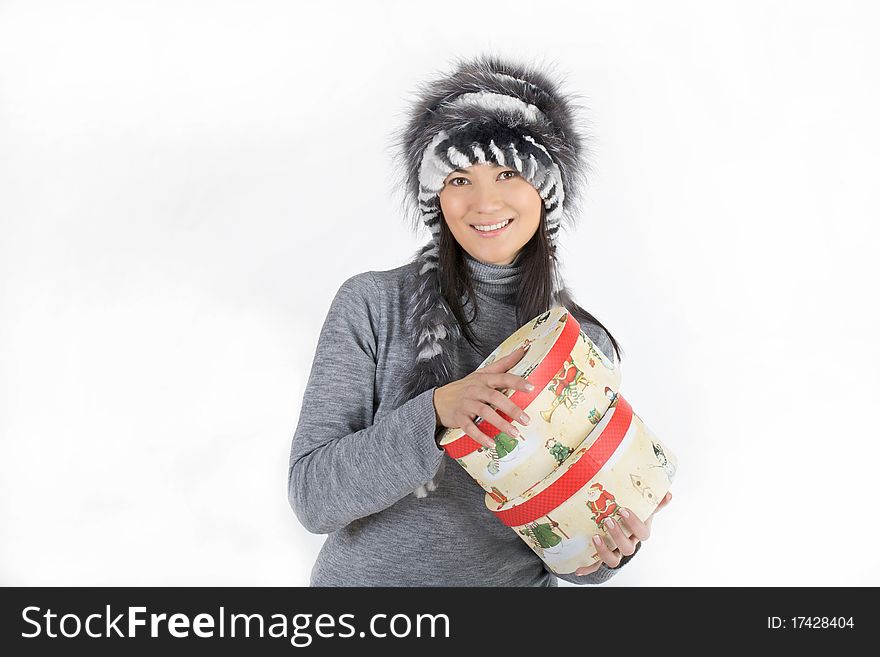 Girl Asian appearance in a fur hat holding a gift box and smiling. Girl Asian appearance in a fur hat holding a gift box and smiling