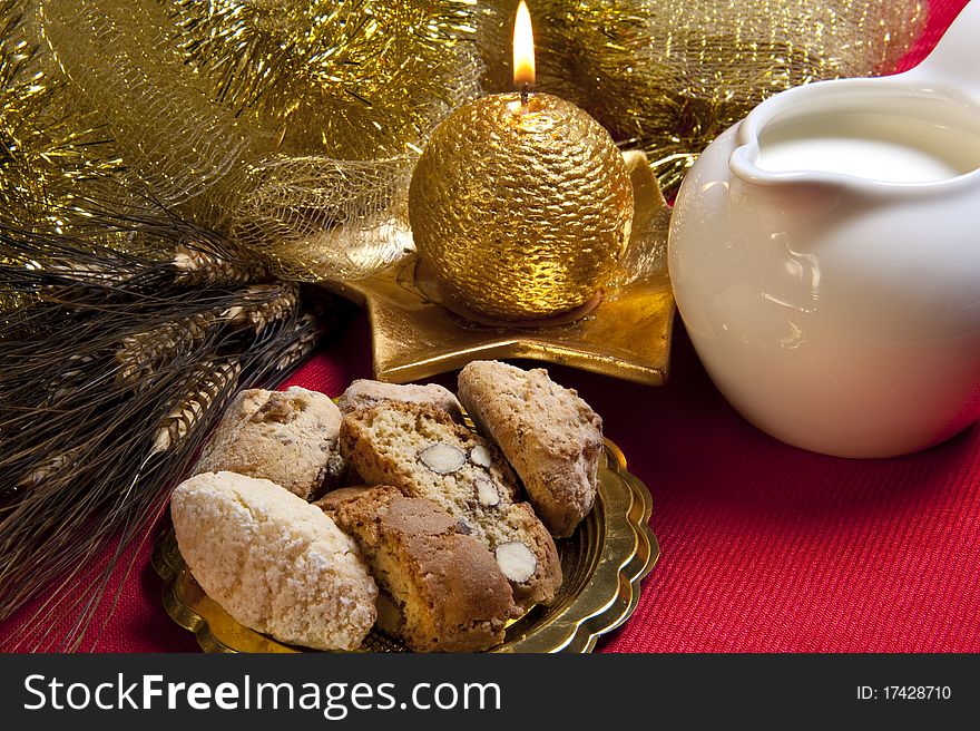 Biscuits, milk, candles and Christmas decorations on red background. Biscuits, milk, candles and Christmas decorations on red background