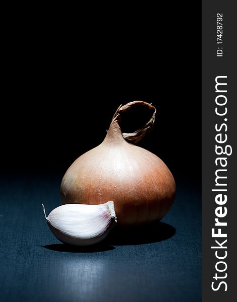 Onion and garlic clove on black background