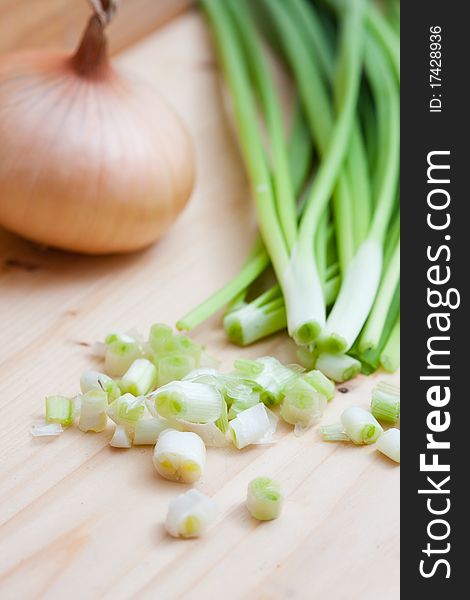 Onion and spring onions on wooden board