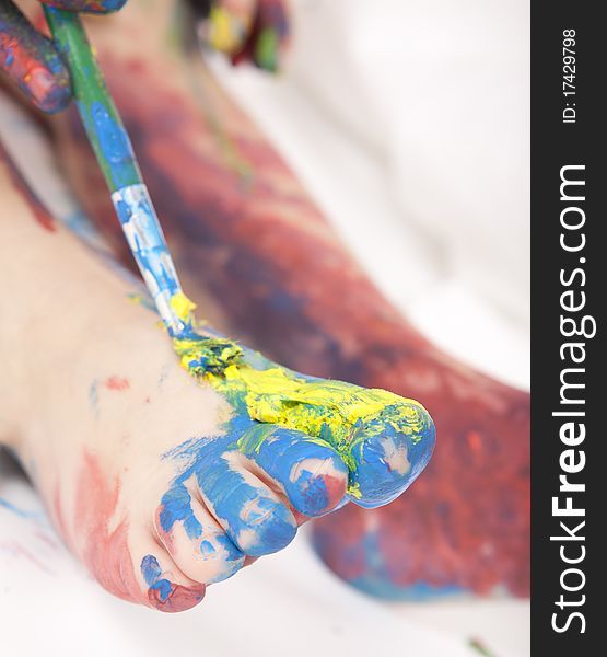 Beautiful baby covered in bright paint with paint brush. Beautiful baby covered in bright paint with paint brush