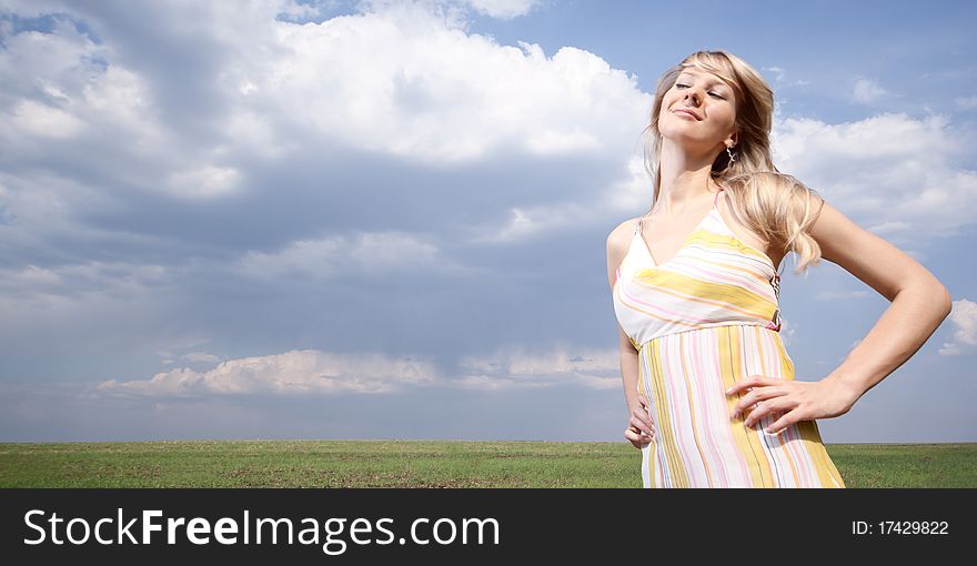 Outdoor portrait of a young lady on a blue cloudy sky background. Outdoor portrait of a young lady on a blue cloudy sky background