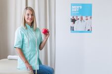 Beautiful Dietitian Is Standing In The Office Holding An Apple Royalty Free Stock Photo