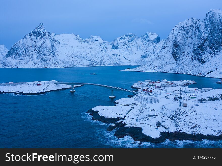 Aerial view of Norwegian fishing village in Reine City, Lofoten islands, Nordland, Norway, Europe. White snowy mountain hills, nature landscape background in winter season. Famous tourist attraction