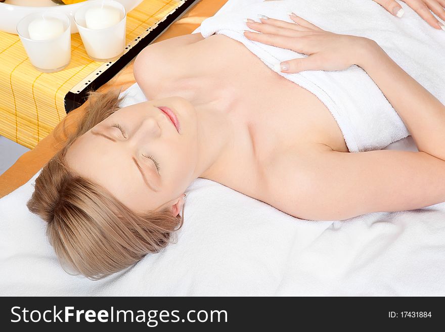Woman in spa on white towel with blond hair