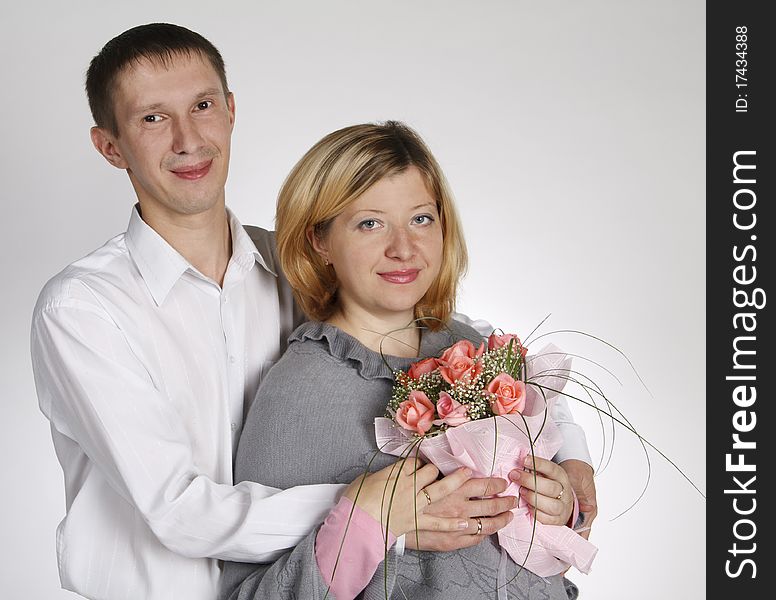 The man embraces the woman, the woman holds a bouquet