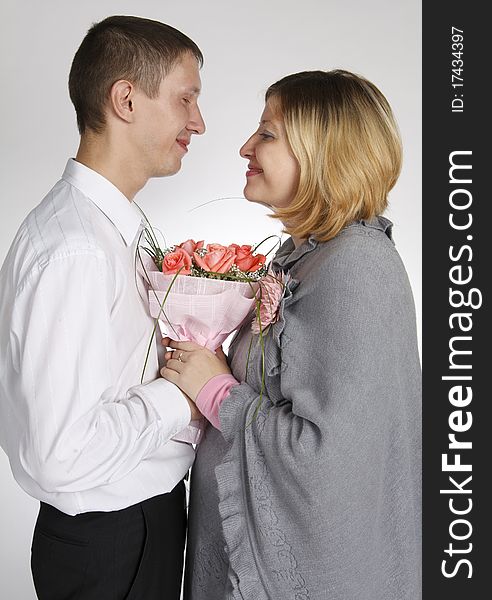 The man and the woman look against each other, hold a bunch of flowers