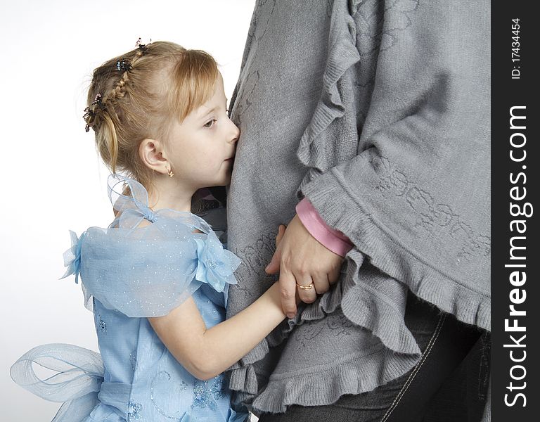 The girl kisses a stomach of the pregnant woman, a studio photo