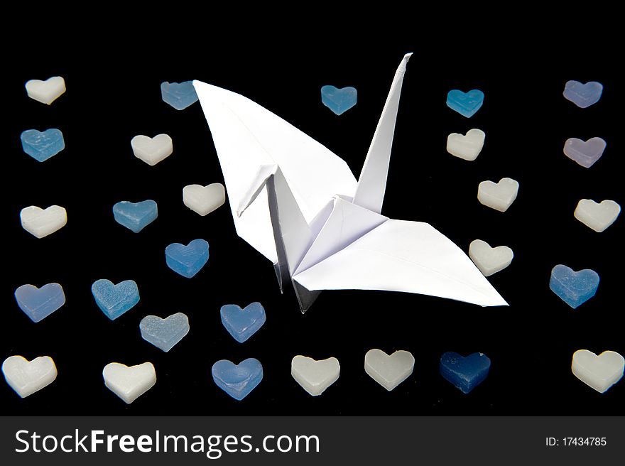 Japanese traditional origami paper crane with heart shape candle isolated on black