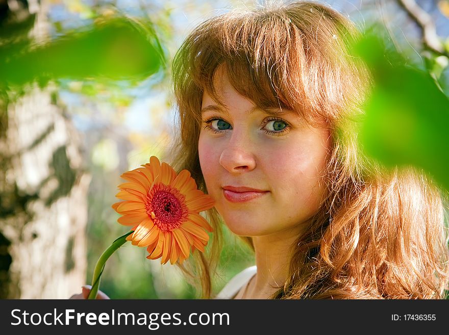 Smiling pretty young woman with flower gerber, standing outdoors in sunlight in spring. Smiling pretty young woman with flower gerber, standing outdoors in sunlight in spring