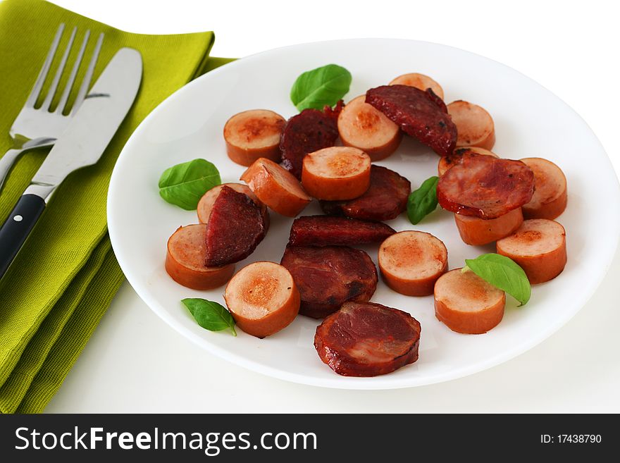 Fried sausages with basil on an white plate