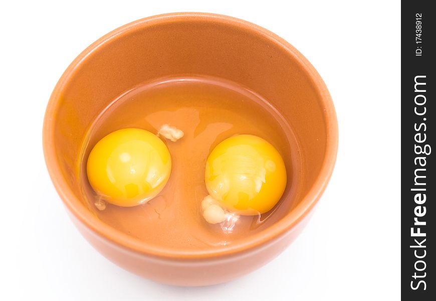 Two eggs are beaten out in a plate which is located on a white background