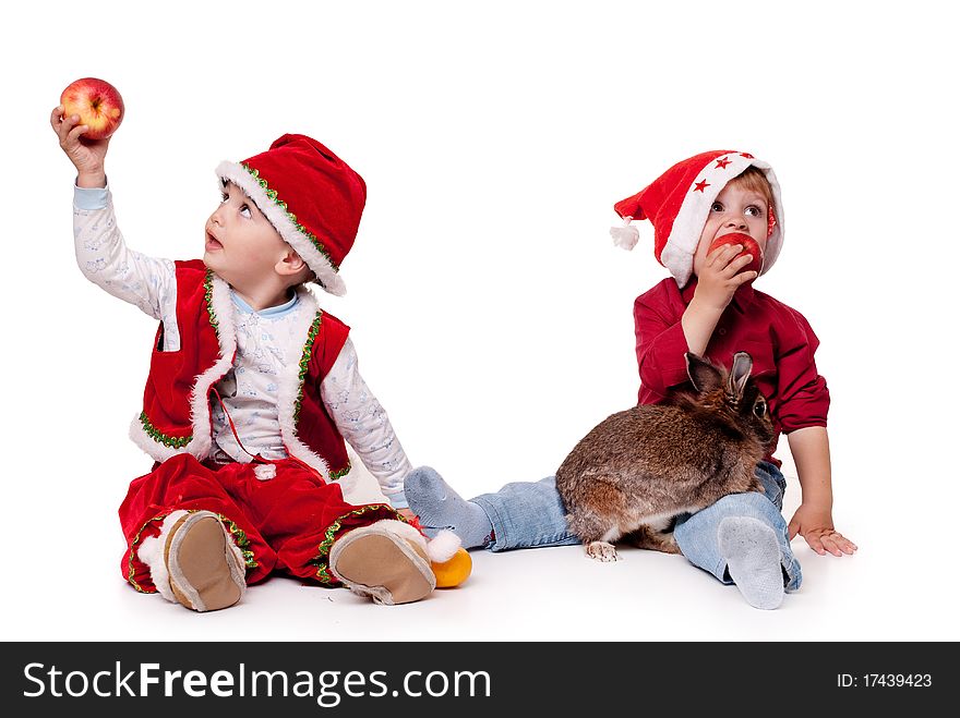 Two kids in Santa hats with a rabbit. Two kids in Santa hats with a rabbit