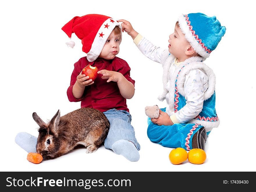 Two kids in Santa hats with a rabbit. Two kids in Santa hats with a rabbit