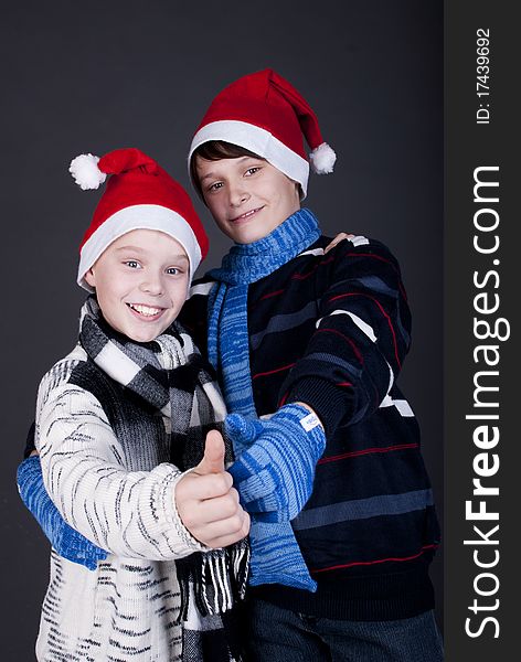 Two gay friend in New Year's hats on a dark studio background. Two gay friend in New Year's hats on a dark studio background