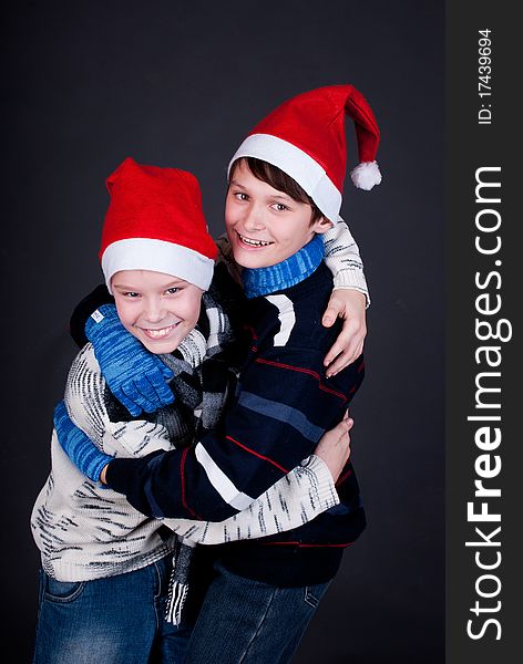 Two gay friend in New Year's hats on a dark studio background. Two gay friend in New Year's hats on a dark studio background