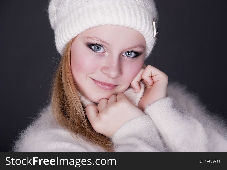 Portrait of the beautiful girl in winter cap on a dark background