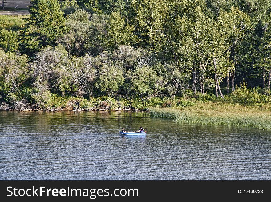 Boat on the lake with a marsh to the right and forested background.