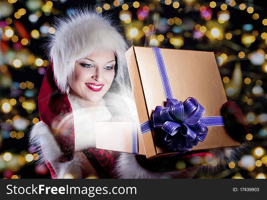 Young woman in santa clothing. Opening a gift box. Young woman in santa clothing. Opening a gift box.