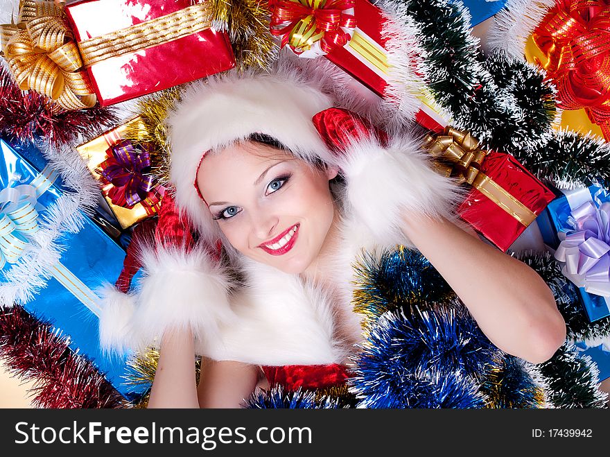 Beautiful girl dressed as Santa Claus lying in a pile of gifts. Beautiful girl dressed as Santa Claus lying in a pile of gifts