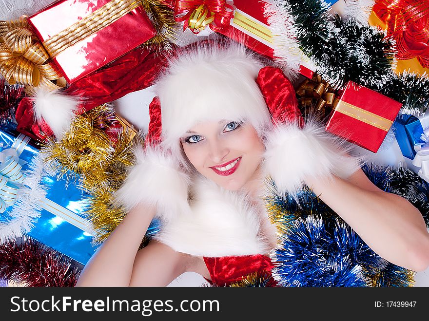 Beautiful woman dressed as Santa Claus lying in a pile of gifts