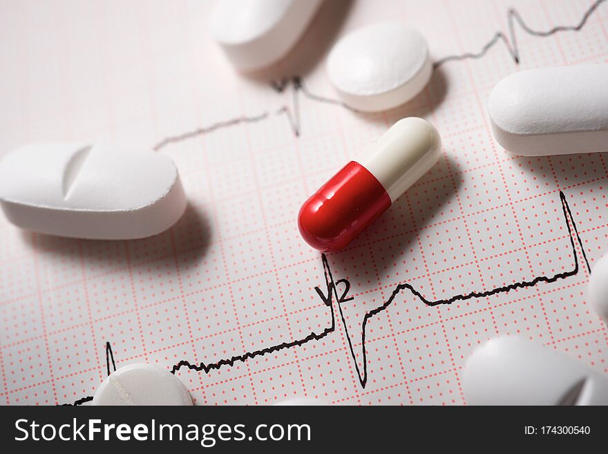 Close up of pills and an electrocardiogram in paper form. Close up of pills and an electrocardiogram in paper form