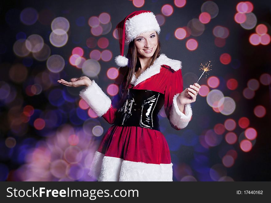 Young beautiful girl in Santa Claus hat holding sparklers