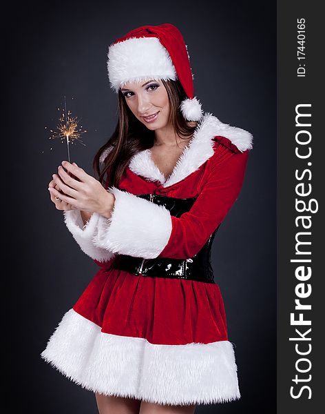 Young beautiful woman in Santa Claus hat holding sparklers