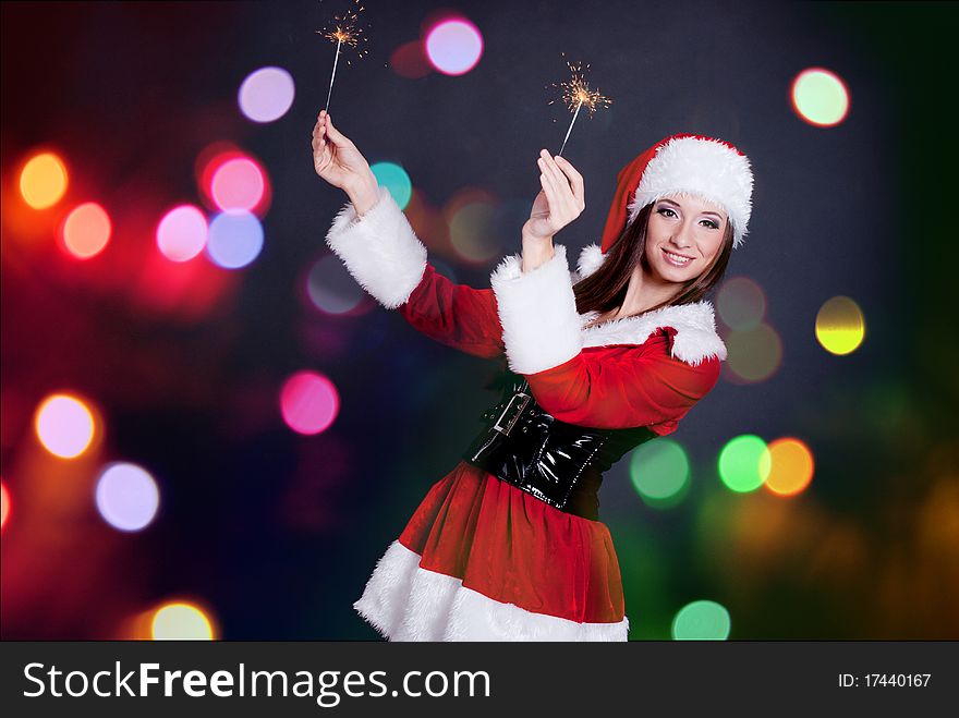 Young beautiful girl in Santa Claus hat holding sparklers. Young beautiful girl in Santa Claus hat holding sparklers