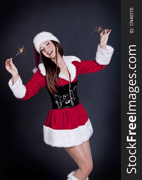 Young beautiful girl in Santa Claus hat holding sparklers