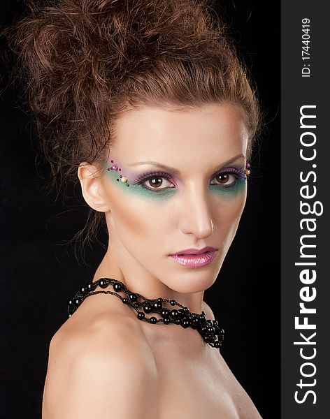 Portrait of young woman with creative make-up on black