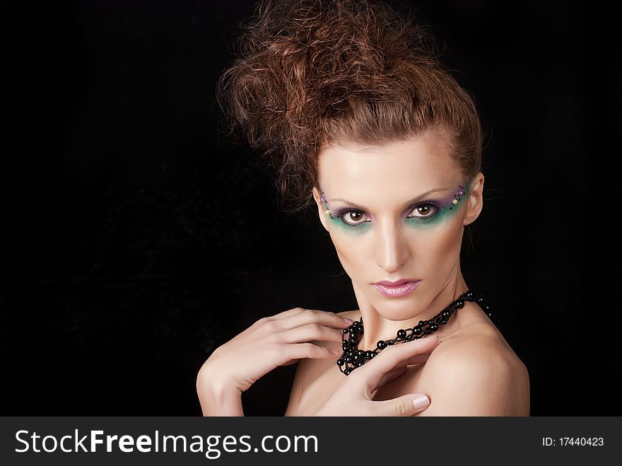 Portrait of young woman with creative make-up on black