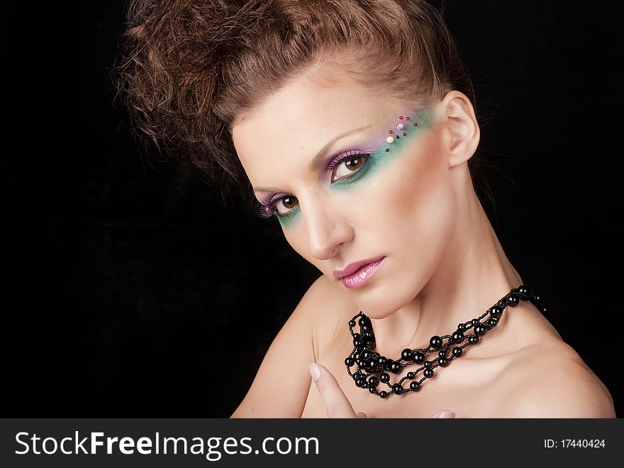 Portrait of young woman with creative make-up on black