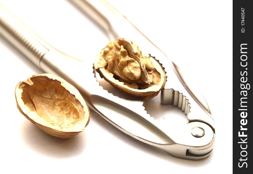 A walnut cracked by a nutcracker on white background. A walnut cracked by a nutcracker on white background