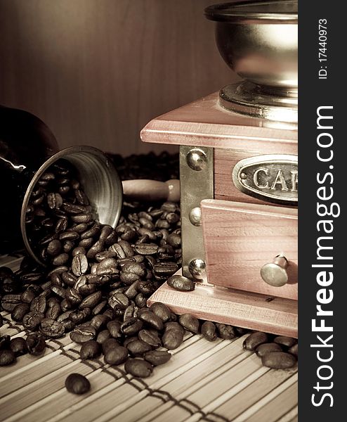 Coffee beans, copper pot and grinder on sacking