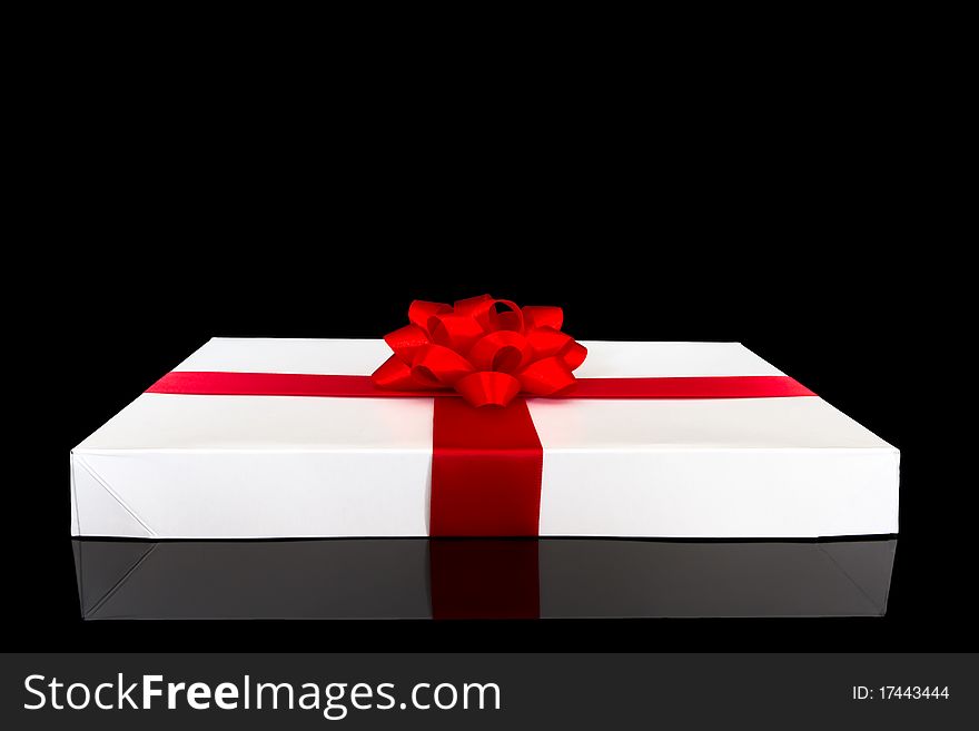 Gift box with red ribbon and bow isolated on black