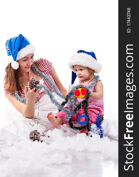 Mother and daughter in Santa's hat sitting in artificial snow isolated on white. Mother and daughter in Santa's hat sitting in artificial snow isolated on white