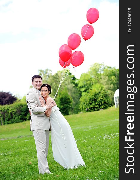 Groom and bride with balloons on green field. Groom and bride with balloons on green field