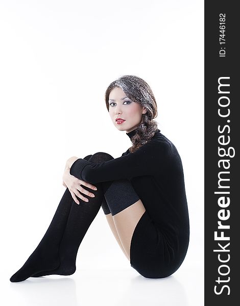 Fashion model wearing winter clothes with snow on her hair posing in studio