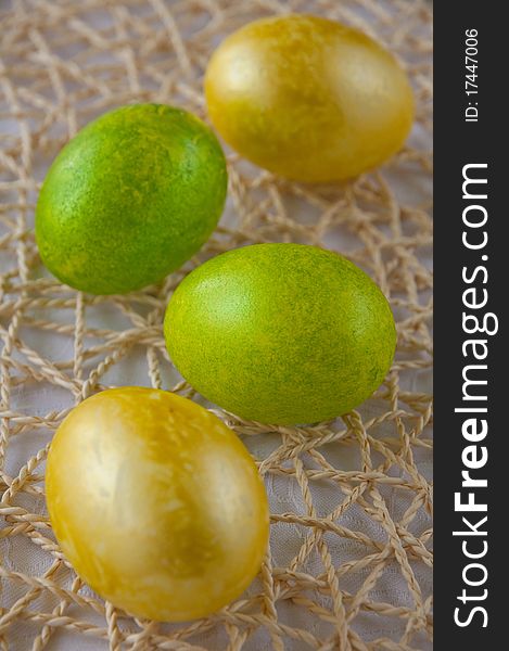 Green and yellow easter eggs on straw placemat