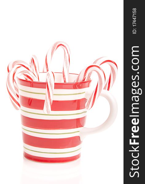Christmas and new year mug full of sweet papermint candy canes with red and green stripes isolated on a white background. Christmas and new year mug full of sweet papermint candy canes with red and green stripes isolated on a white background