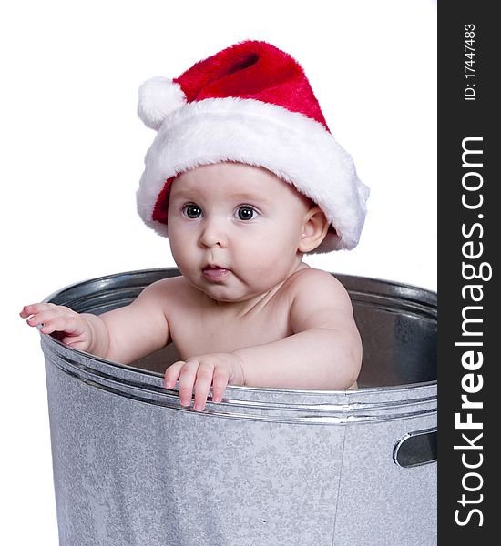 Baby wearing Santa hat and holding onto the sides of a wash basin. Baby wearing Santa hat and holding onto the sides of a wash basin.