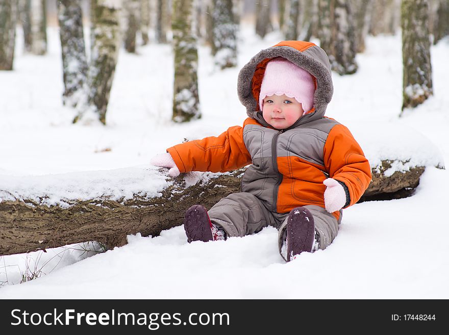 Baby sit on snow in park near tree