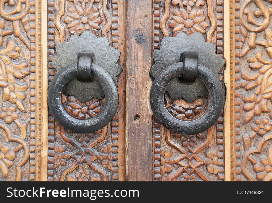 Wrought iron door handles on ornate wooden door