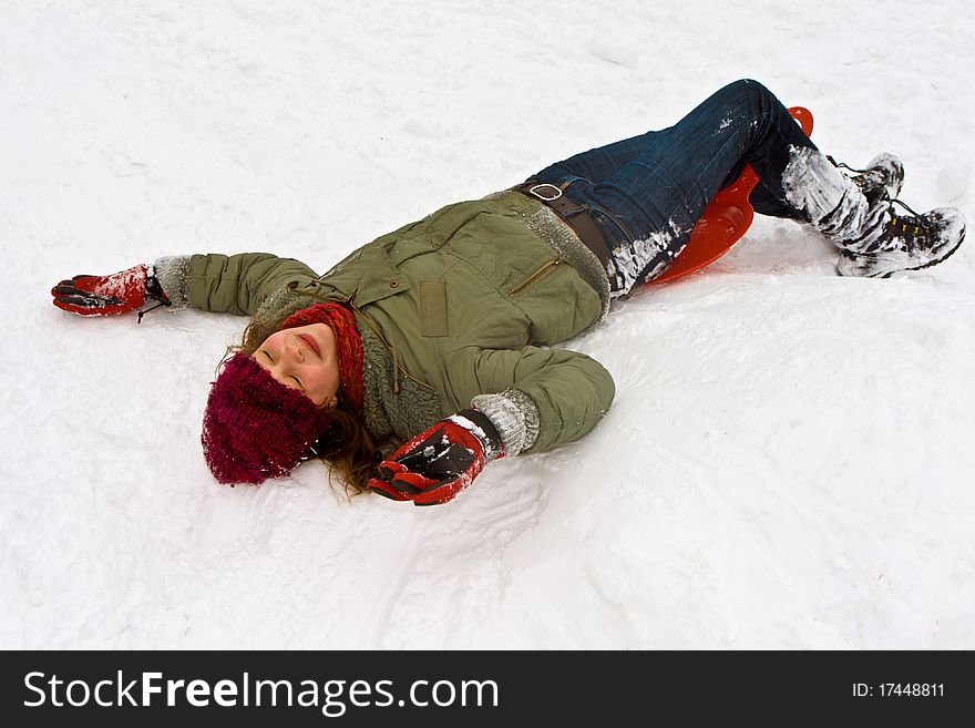 Girl has fun lying in the snow while it is snowing