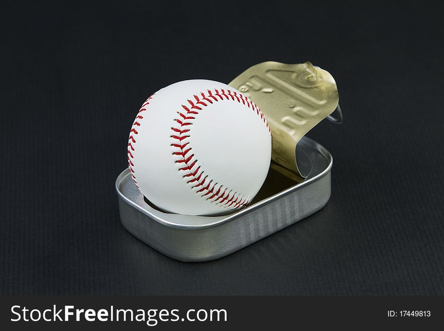 Surprising image of opened sardine can releasing a baseball reflects sports passions and obsessions. Surprising image of opened sardine can releasing a baseball reflects sports passions and obsessions