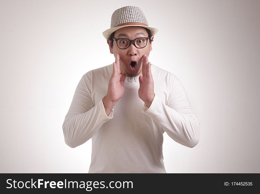 Portrait of young funny Asian man in white shirt, gesturing shocked or surprised expression with mouth open, while standing over white background. Portrait of young funny Asian man in white shirt, gesturing shocked or surprised expression with mouth open, while standing over white background