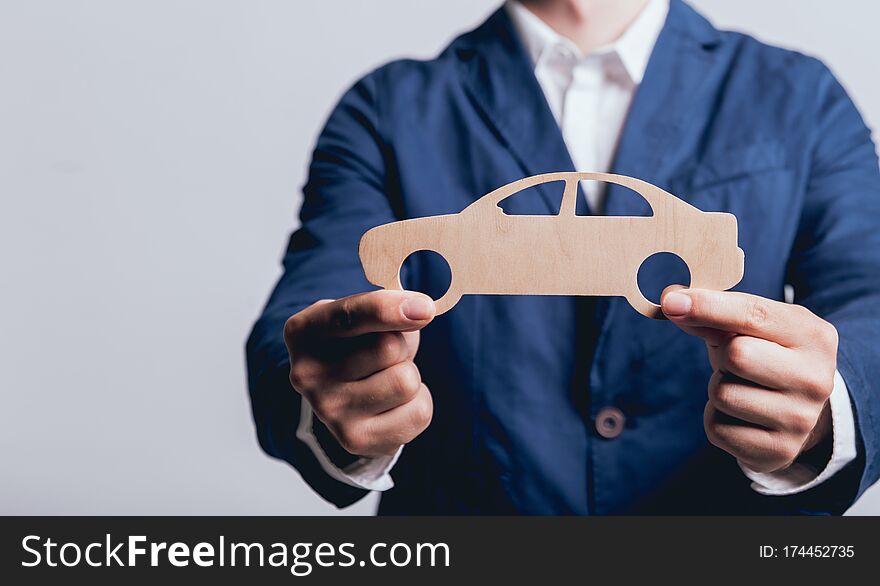 Man proposing signing a car insurance policy, the agent is holding the wooden car model. Car insurance concept. Man proposing signing a car insurance policy, the agent is holding the wooden car model. Car insurance concept.